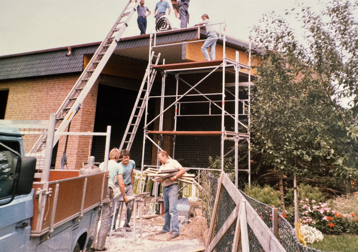 Historische Aufnahme: das Team von Reiners Dachbau bei der Dacheindeckung eines Neubaus mit Gerüst und Leiter